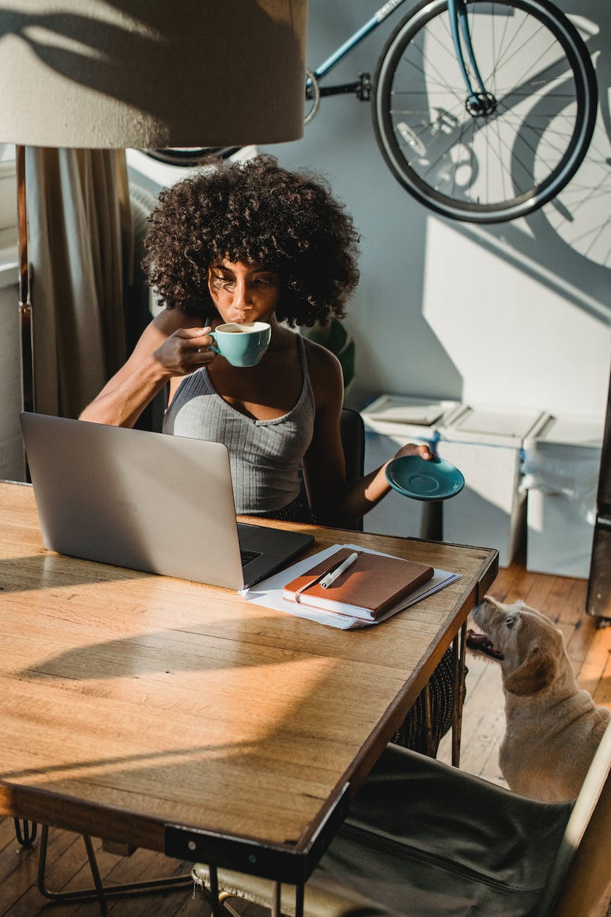 black lady working remotely on netbook and drinking coffee