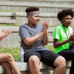a group of kids sitting on a concrete bench while clapping hands