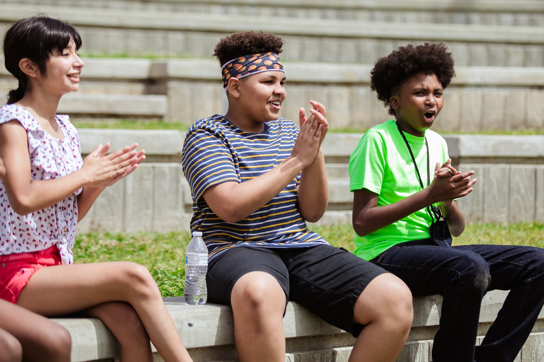 a group of kids sitting on a concrete bench while clapping hands