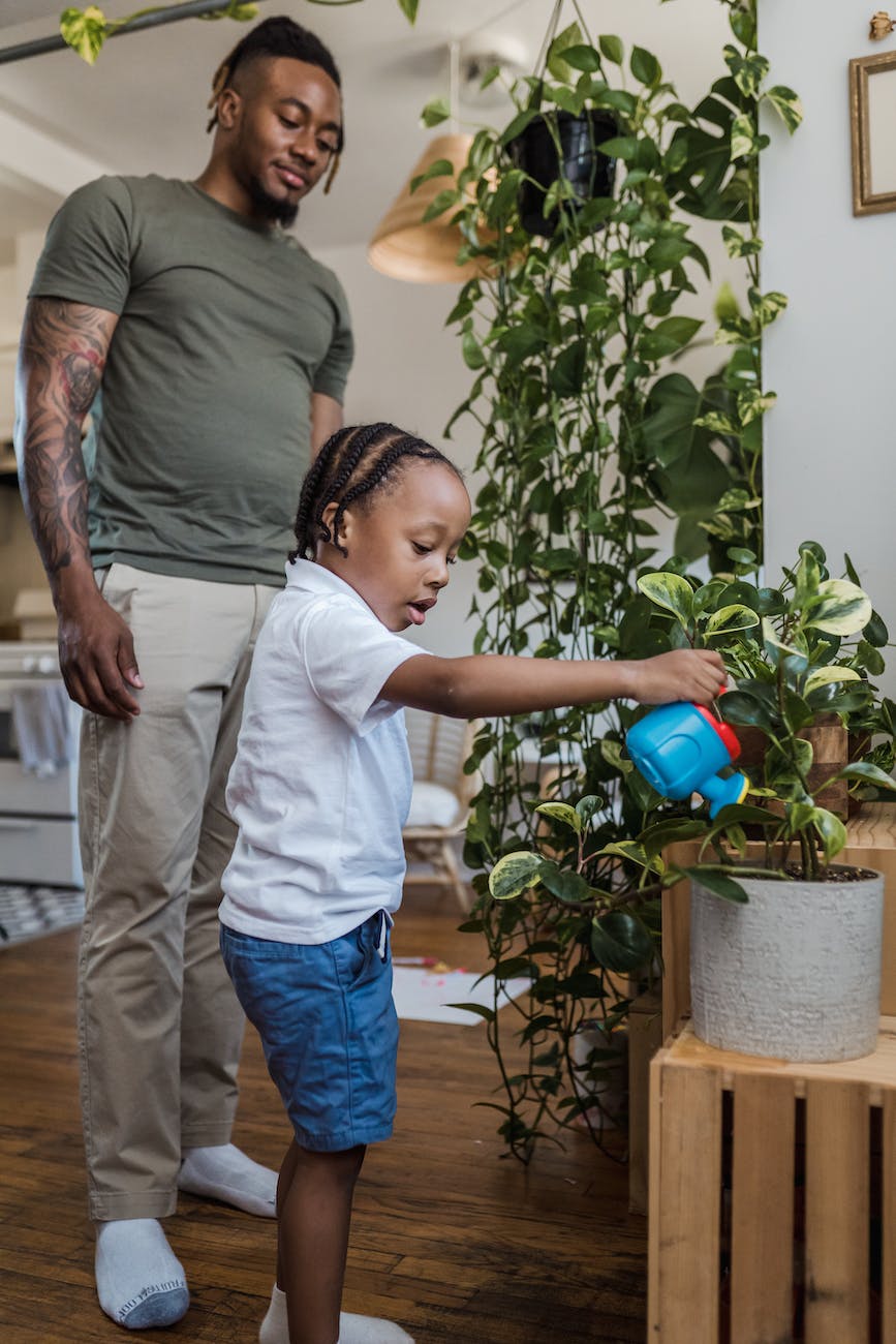 daughter watering houseplants with father