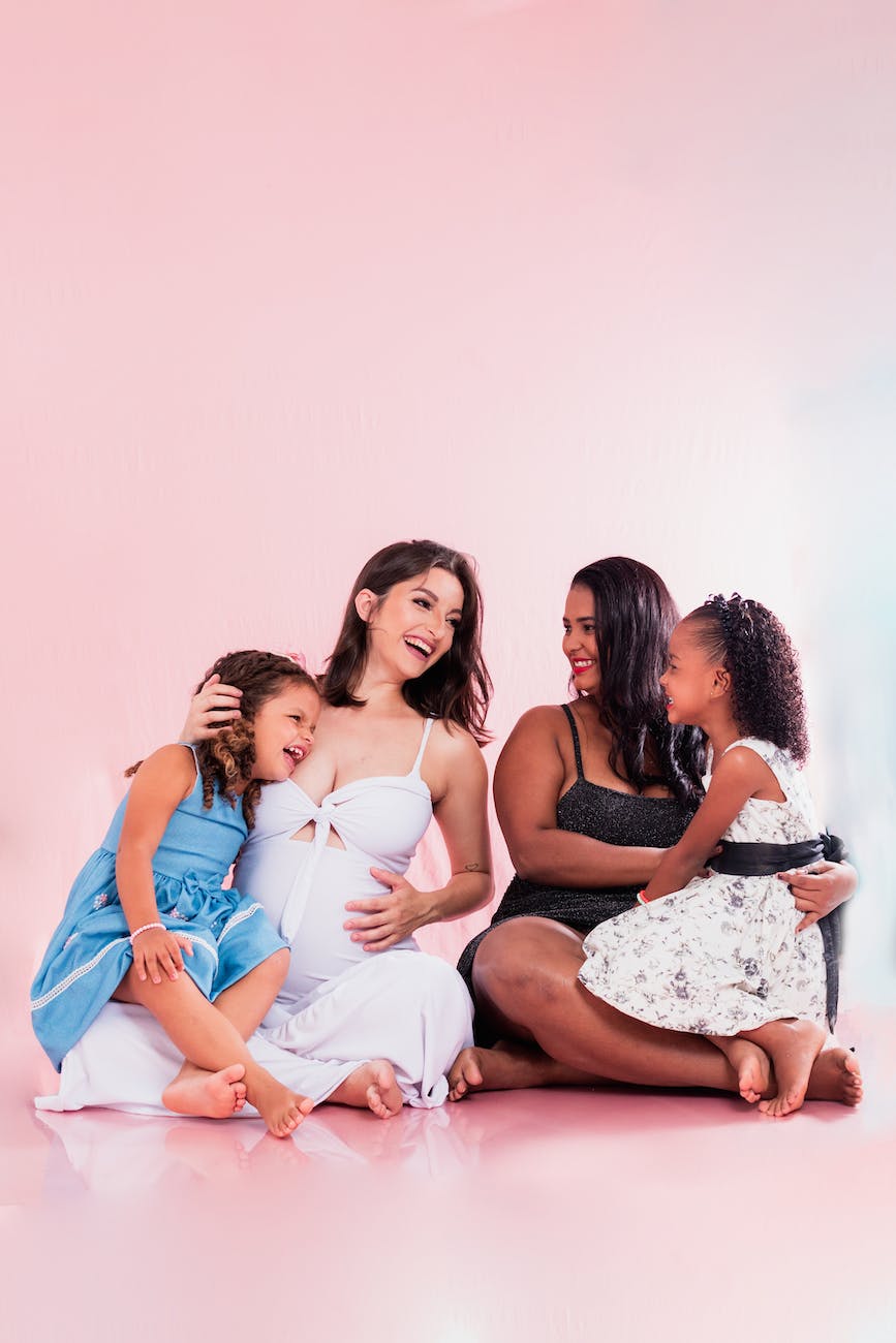 two mothers with daughters sitting on floor in summer dresses