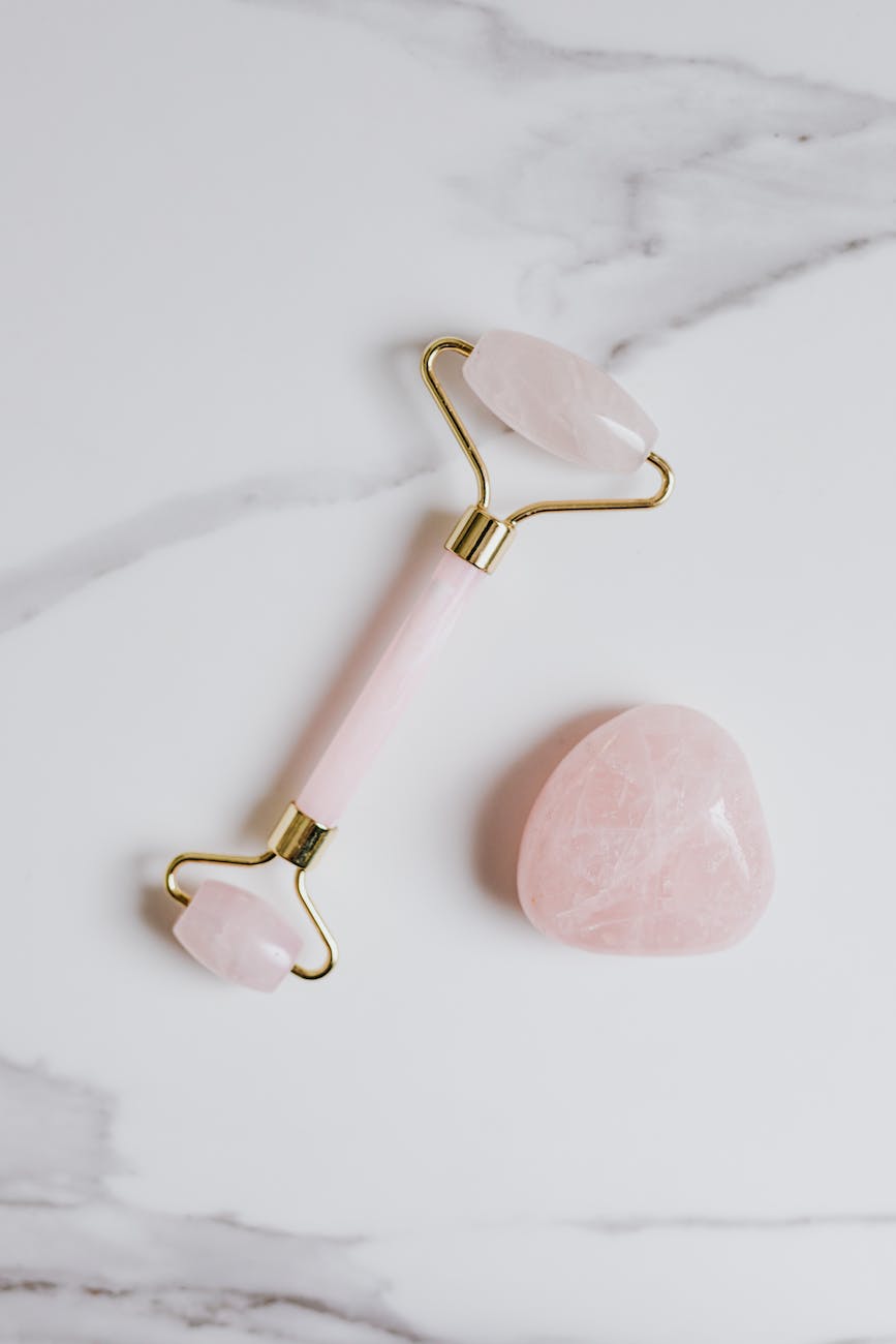 pink and gold jade roller on marble surface