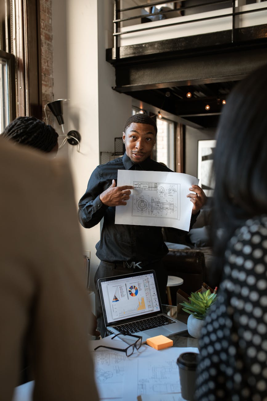 man in blue dress shirt holding white printer paper