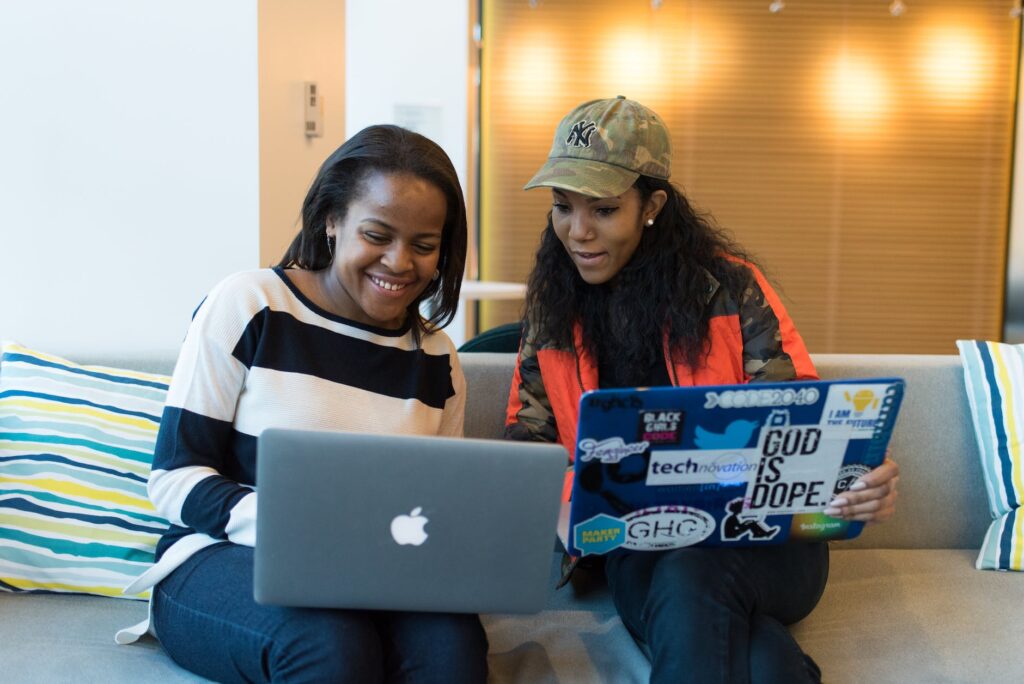 two women holding laptop