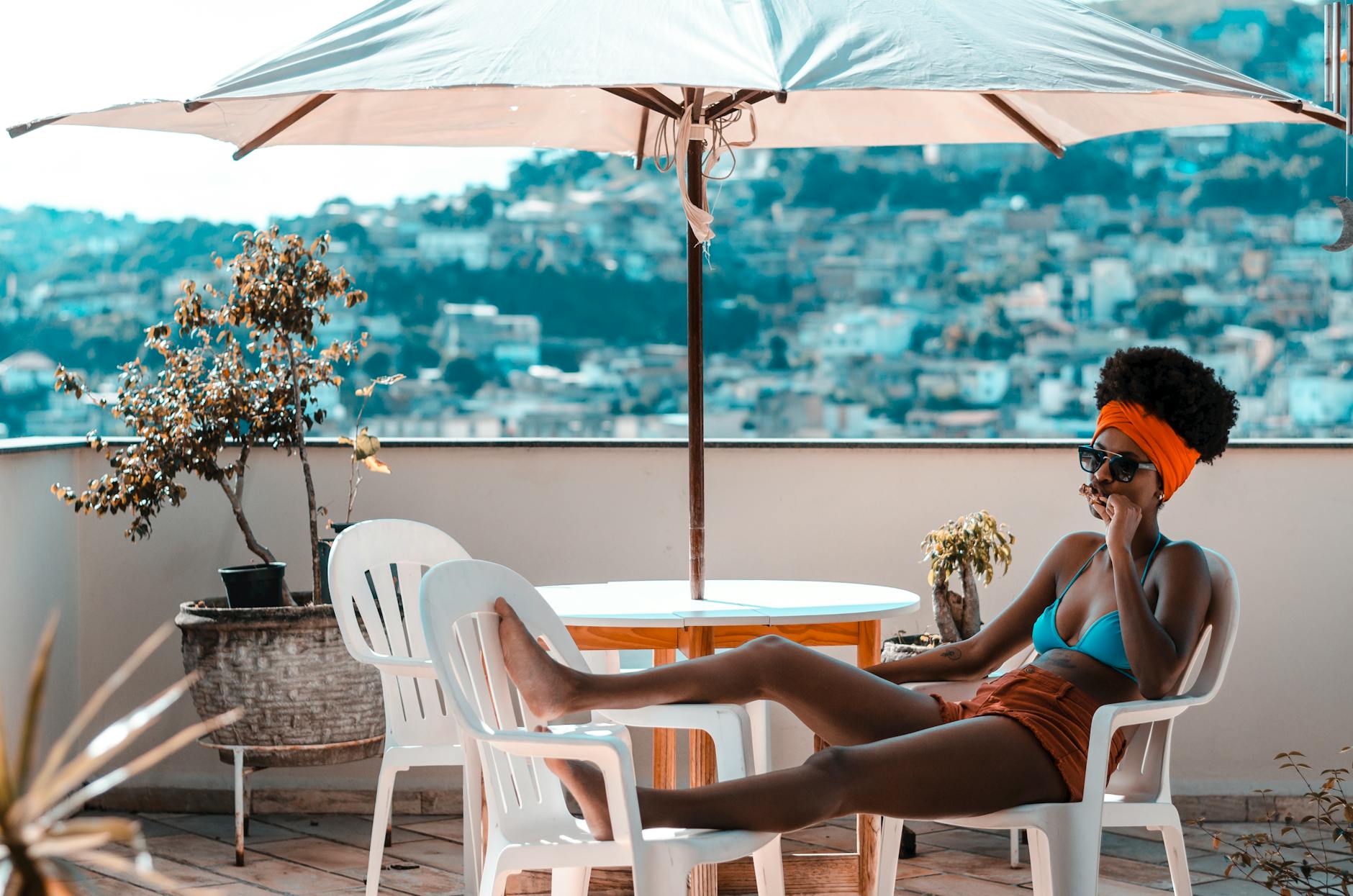 woman sitting on armchair under white patio umbrella