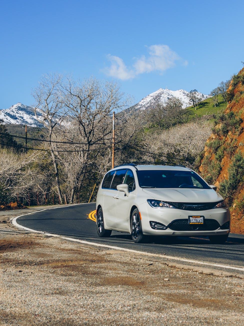 a chrysler pacifica minivan driving on a road in mountains