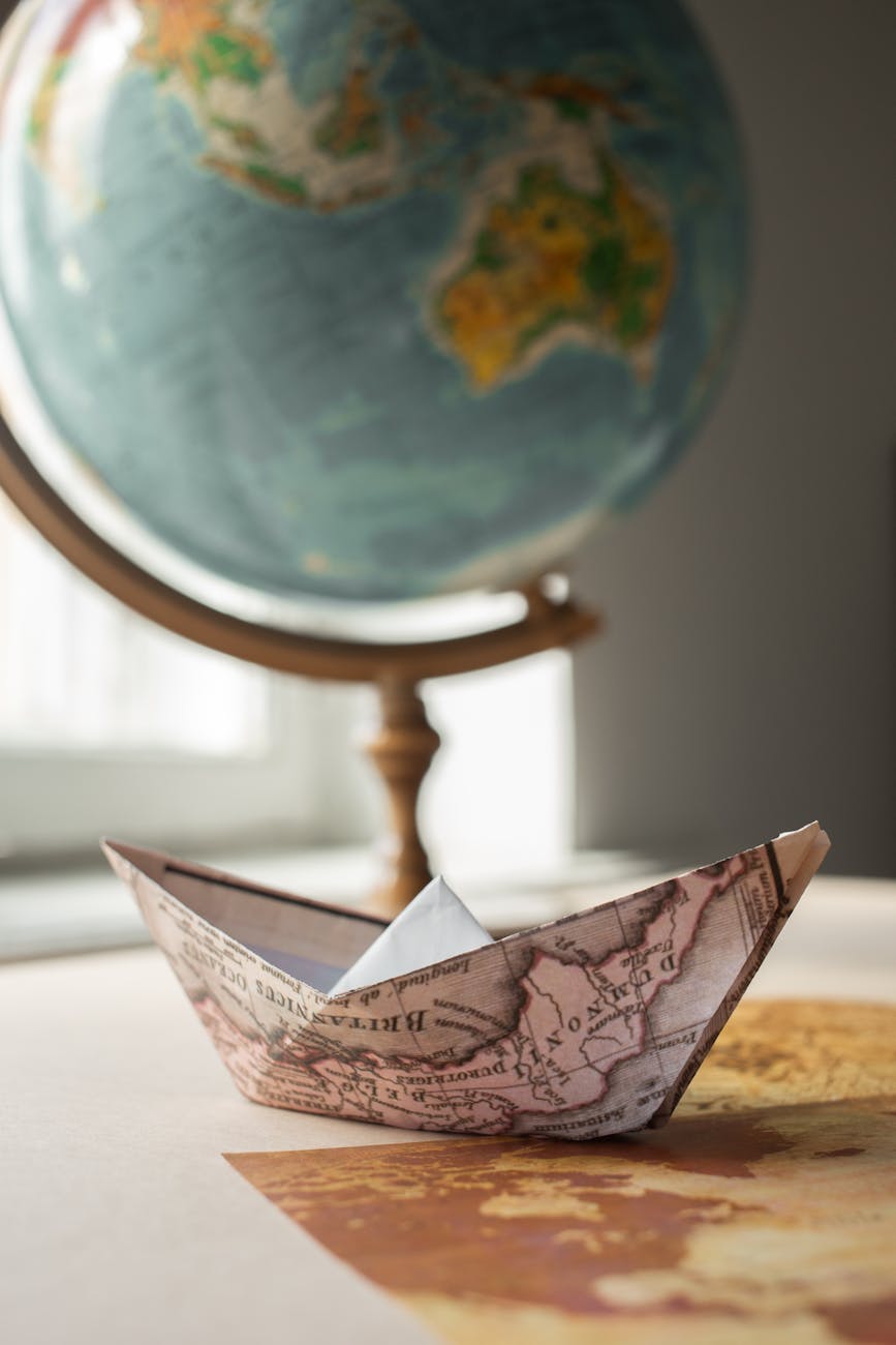 paper boat with map near globe