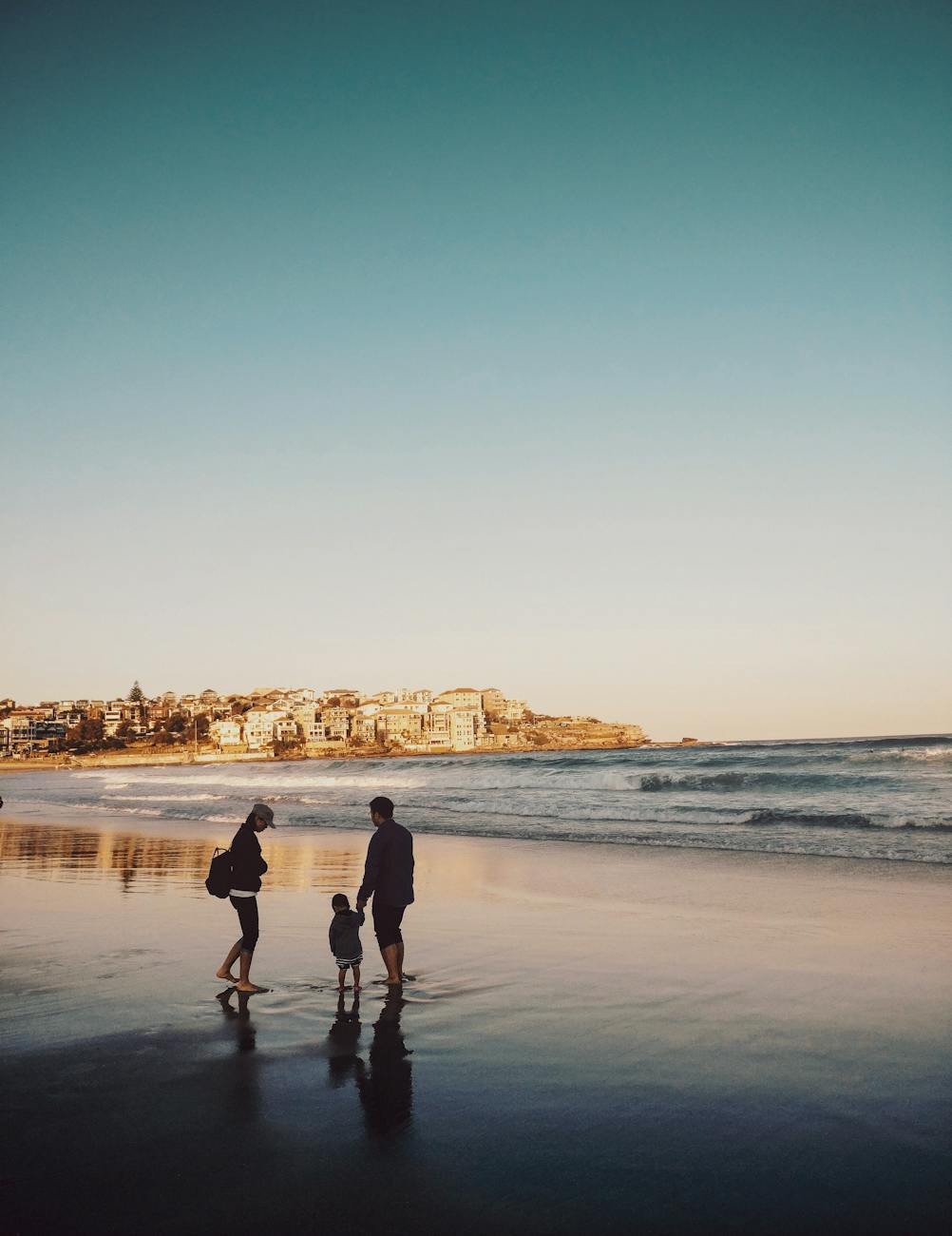 man and woman walking with boy in seashore