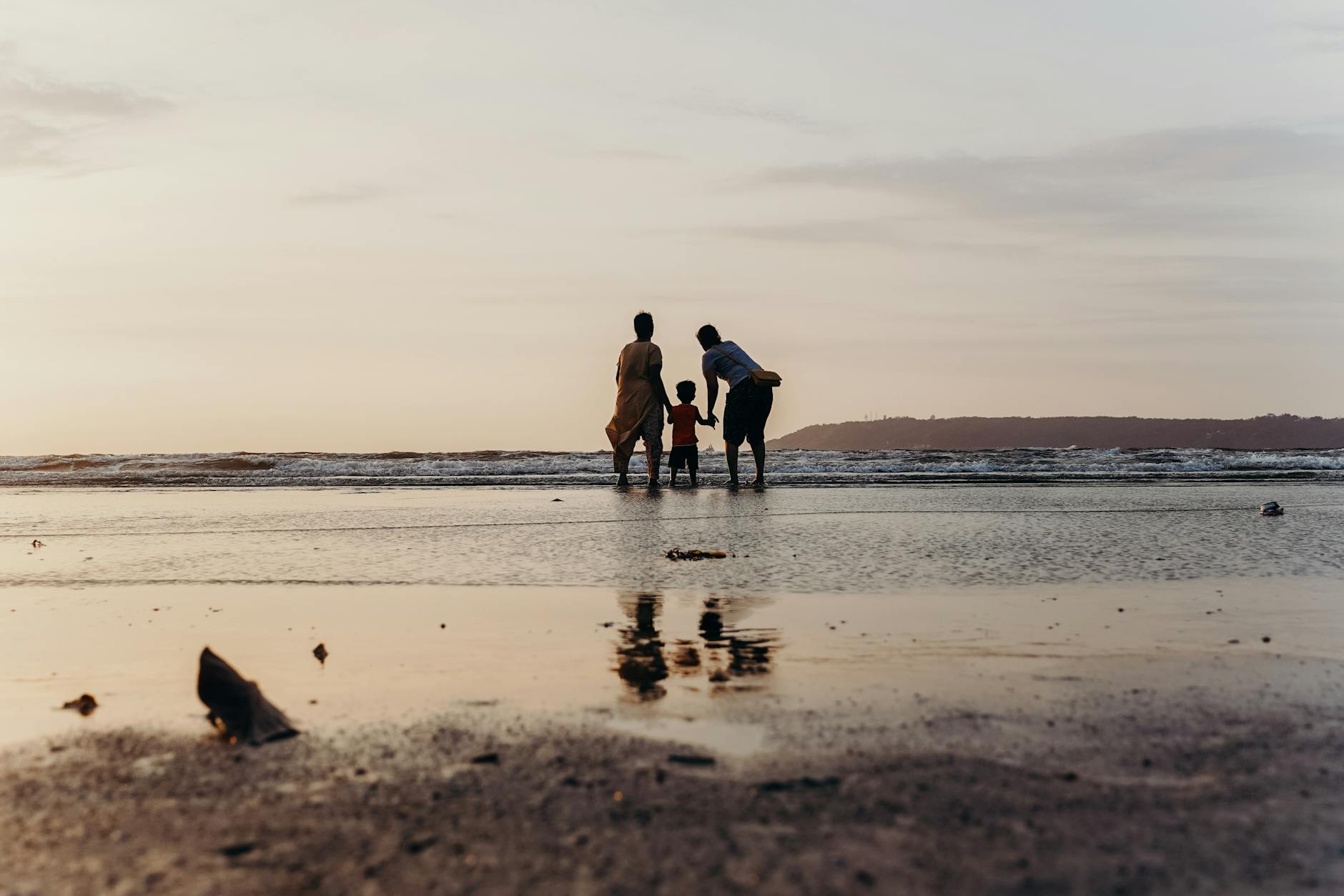 photo of three people standing on beach