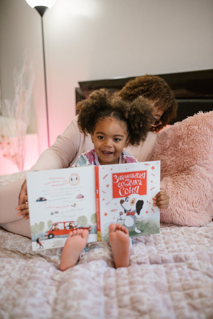 mother and daughter reading book in bed
