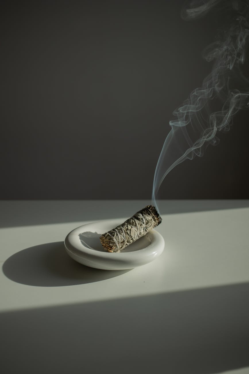 a burning incense on a white plate standing on a white table
