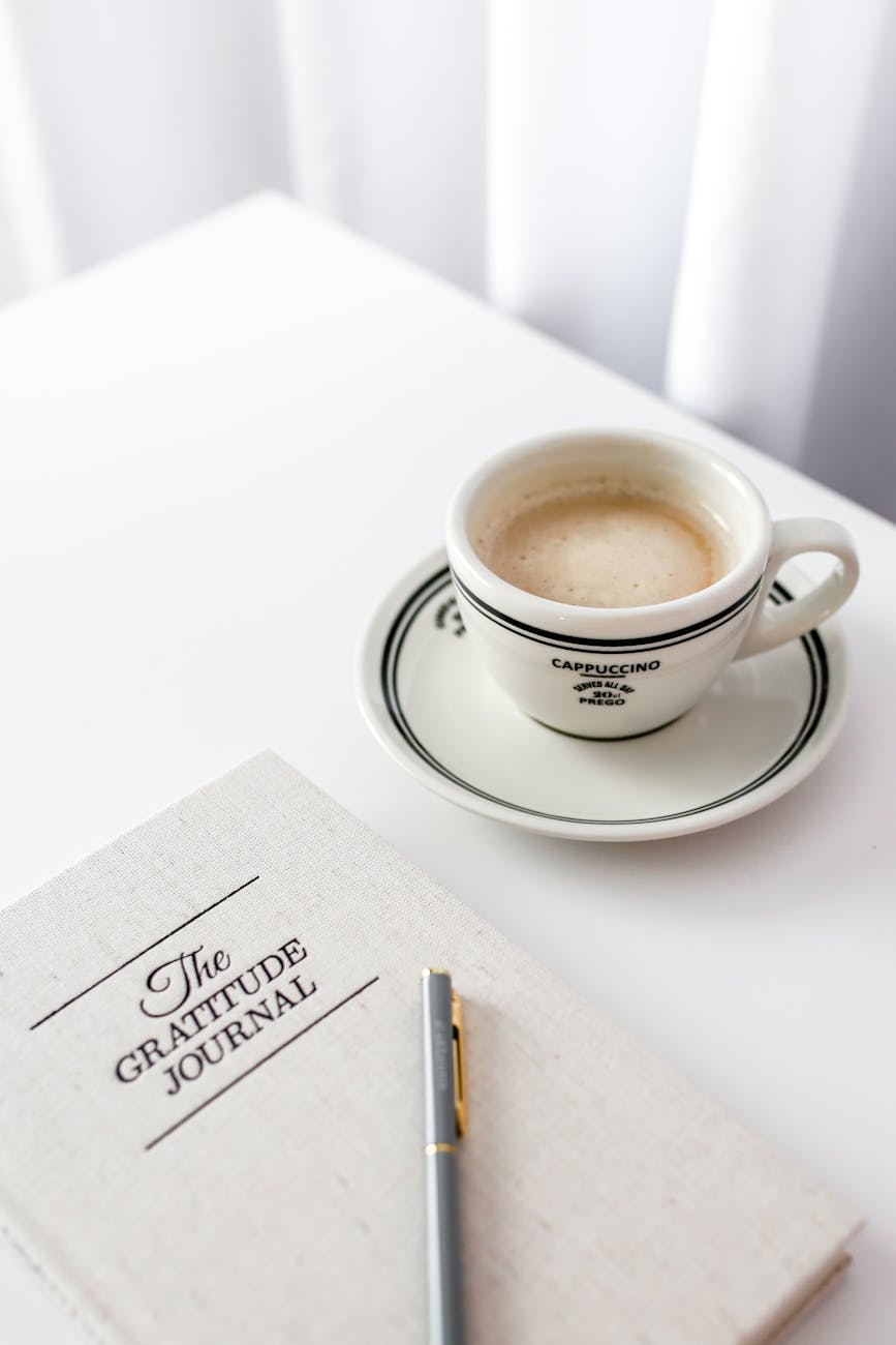 minimalist cappuccino and gratitude journal flat lay
