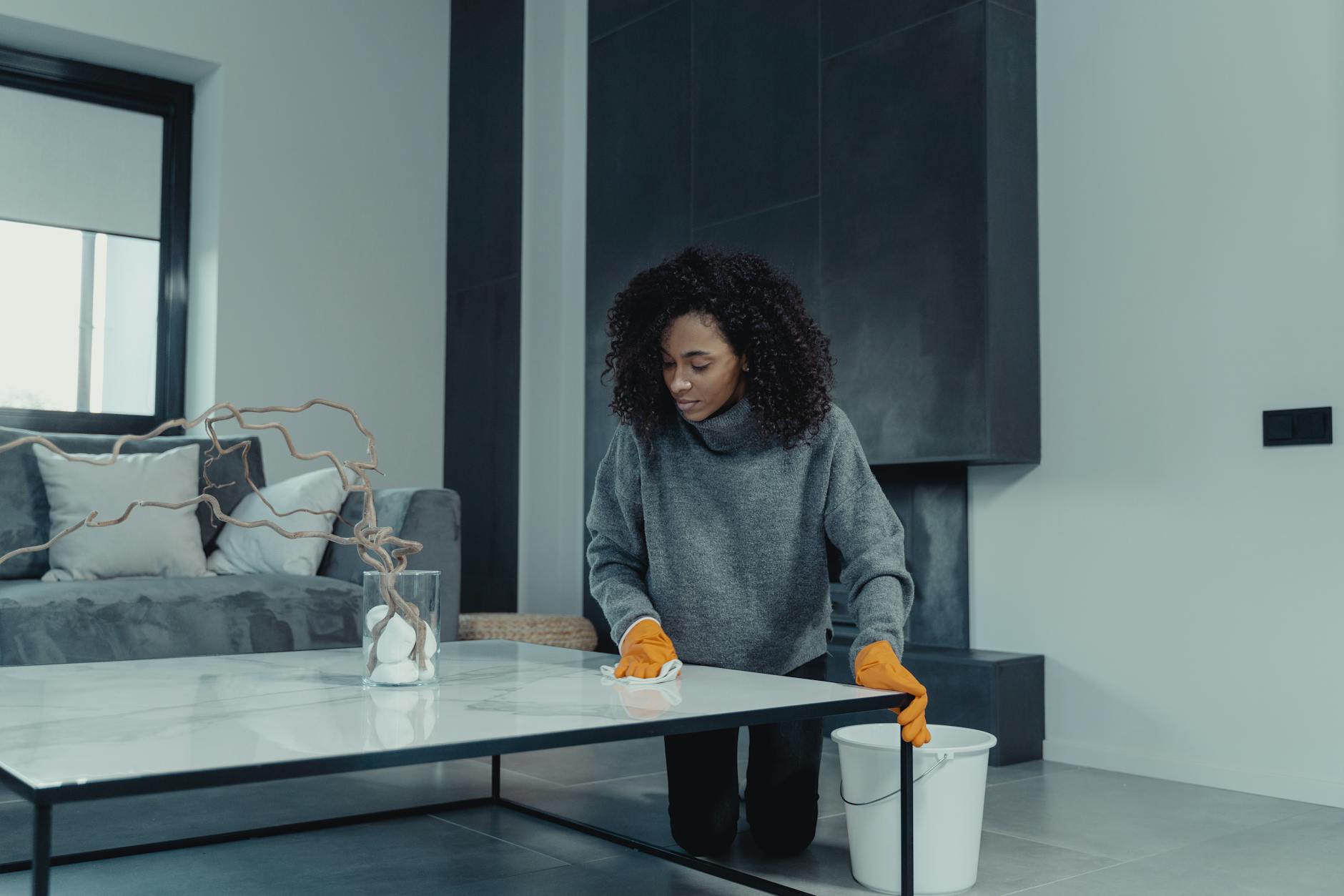 woman in gray sweater standing near table