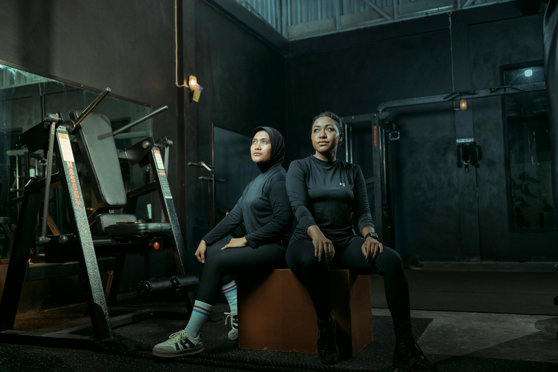 two women in gym gear sitting in modern gym