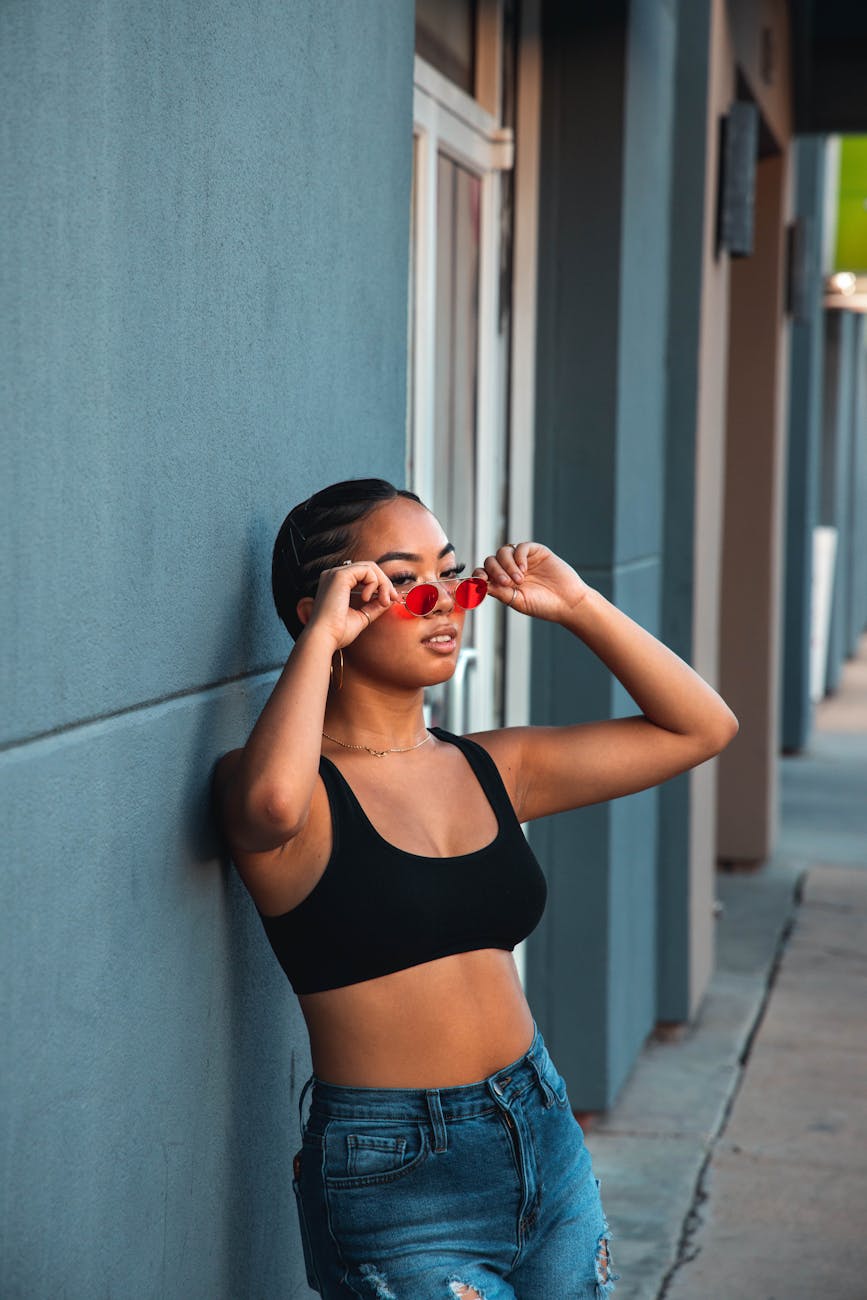 trendy woman in sunglasses leaning on urban wall