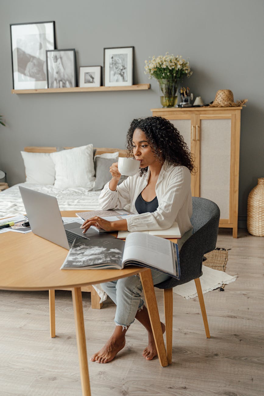 woman in white long sleeve shirt sitting on a chair while using a laptop
